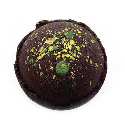 Brown bath bomb with green and yellow speckles on a white background