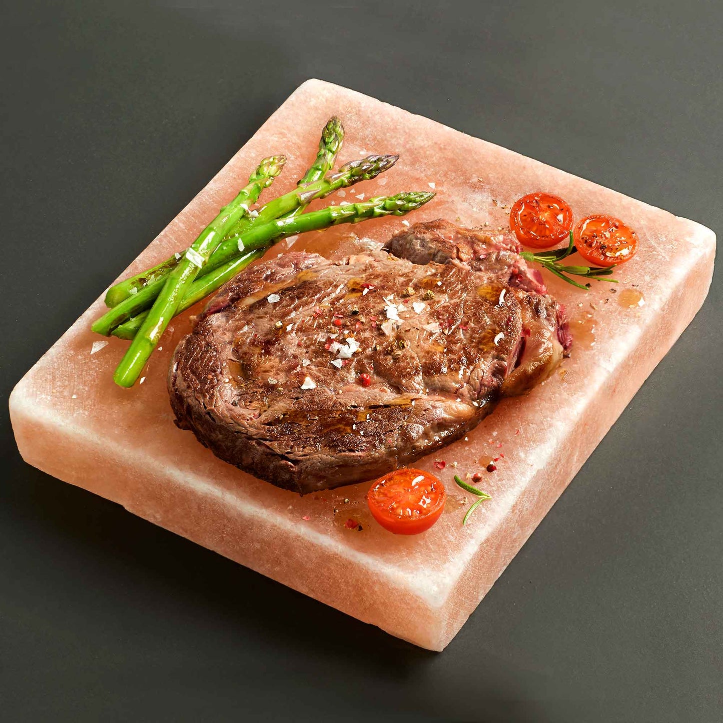 Square Himalayan salt cooking board with steak asparagus and tomatoes